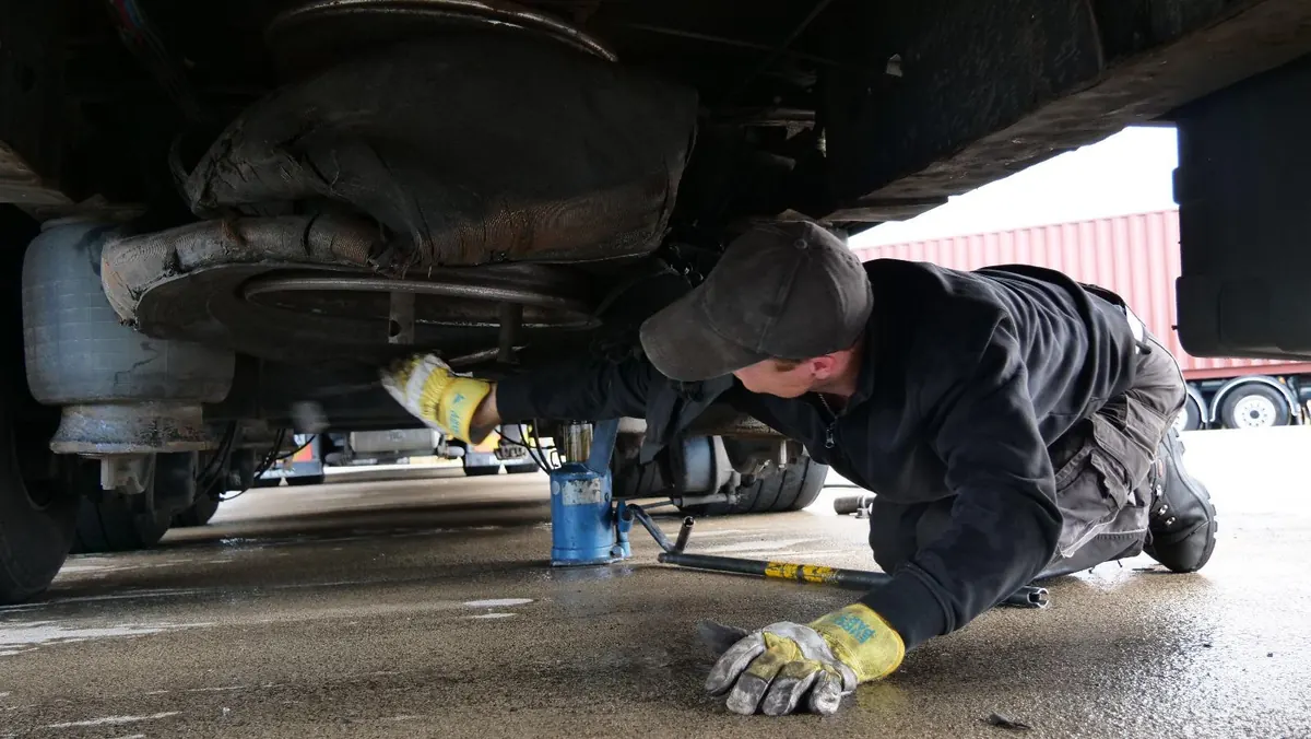Techniker bei Arbeiten unter einem Nutzfahrzeug